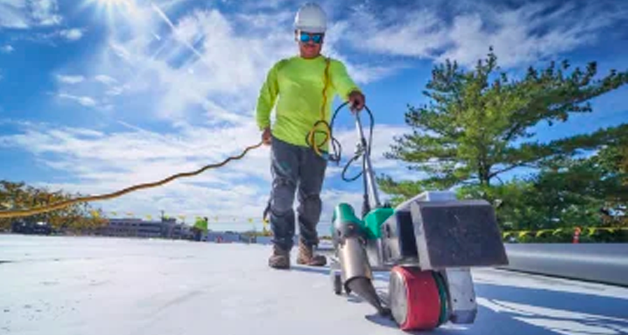 A man is working on a roof with a machine.