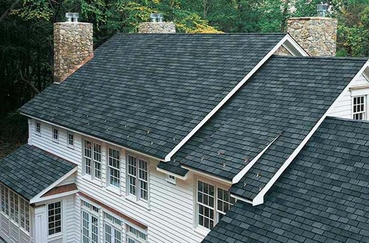 A white house with a black roof and chimneys