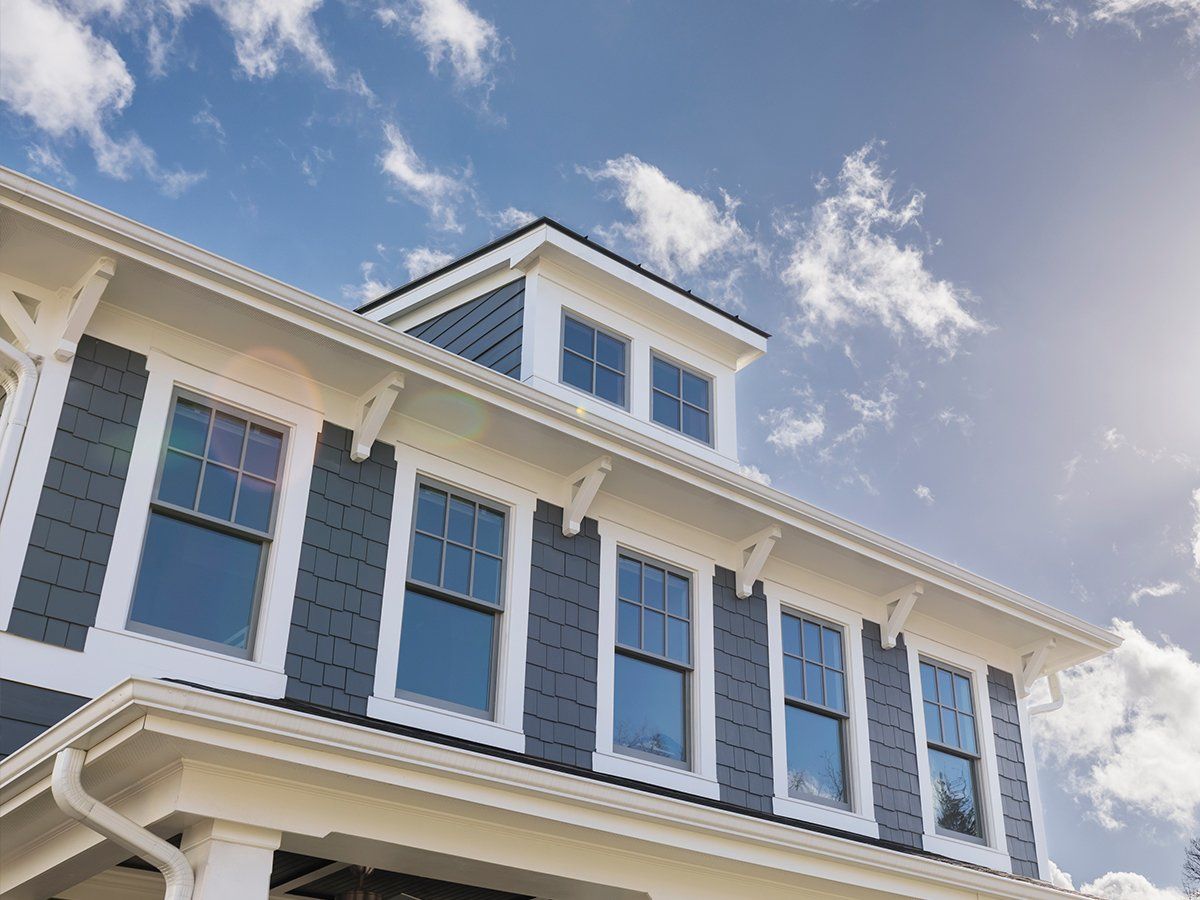 A large white and gray house with a blue sky in the background.