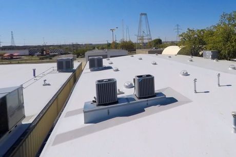 A white roof with two air conditioners on top of it