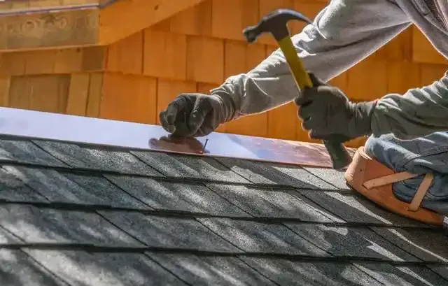 A man is working on a roof with a hammer.