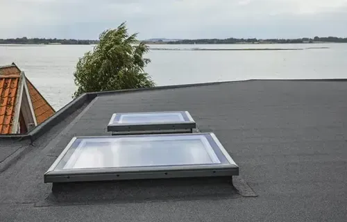 Two skylights on a roof overlooking a body of water