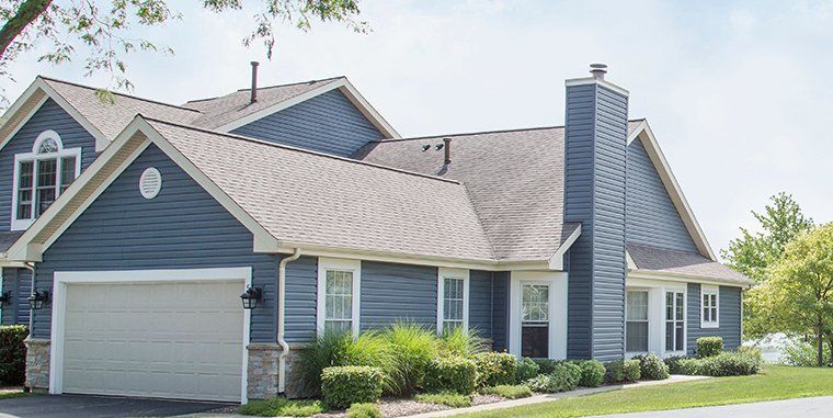 A blue house with a white garage door and a chimney.
