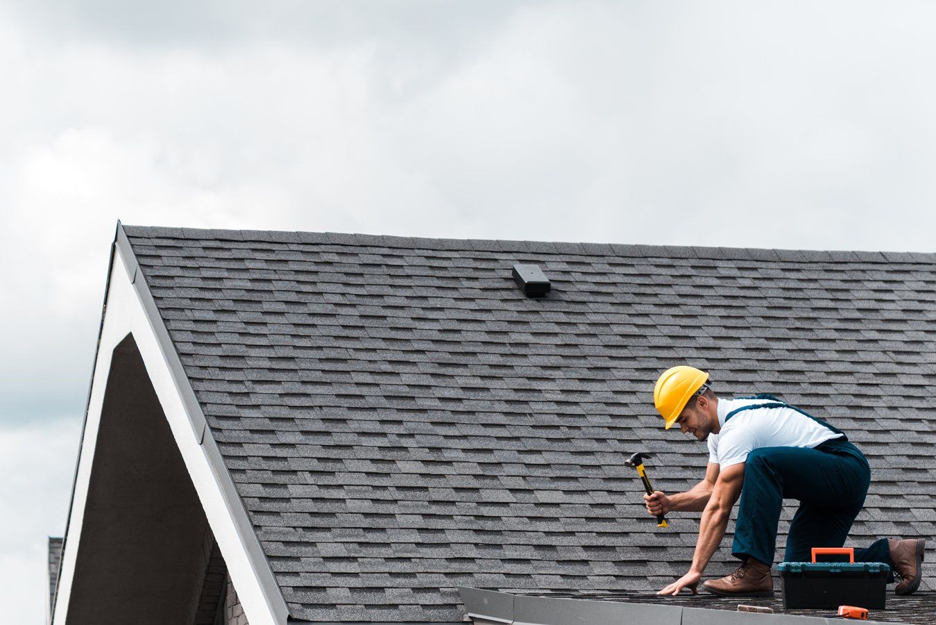 A man is working on a roof with a hammer.