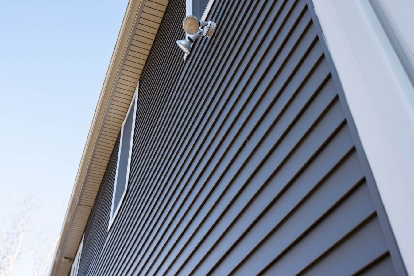 The side of a house with a gray siding and white trim