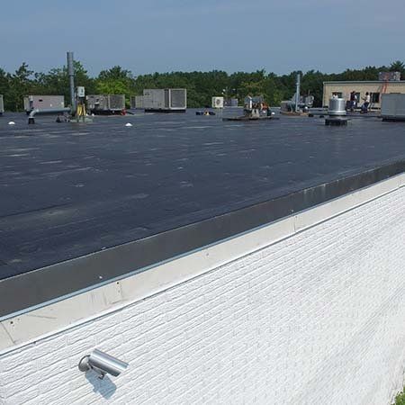 A black roof with a white wall in the foreground
