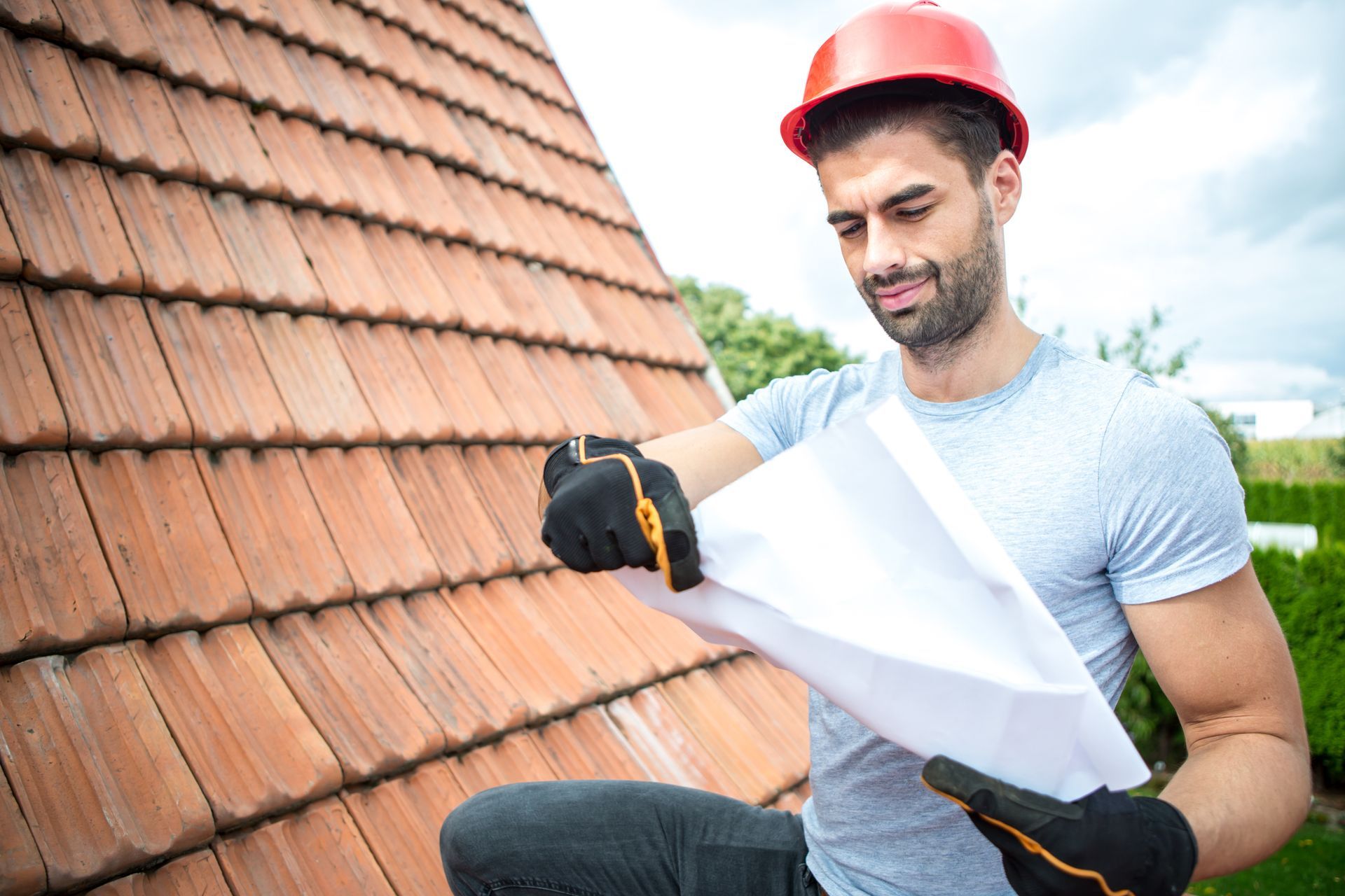 A roofer is looking at plans for replacing a roof. A roofer is looking at plans for replacing a roof.