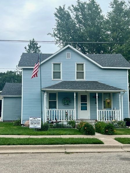 A blue house with an american flag on the front porch — Holmen, WI — Riverland Exteriors Corporation