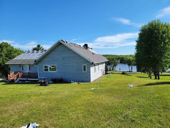 A house is sitting in the middle of a lush green field — Holmen, WI — Riverland Exteriors Corporation