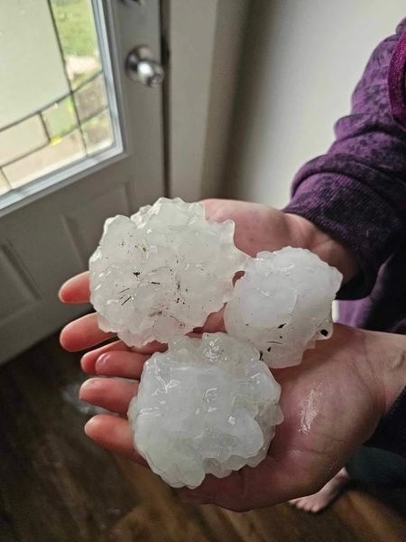 A person is holding a pile of hail in their hands — Holmen, WI — Riverland Exteriors Corporation