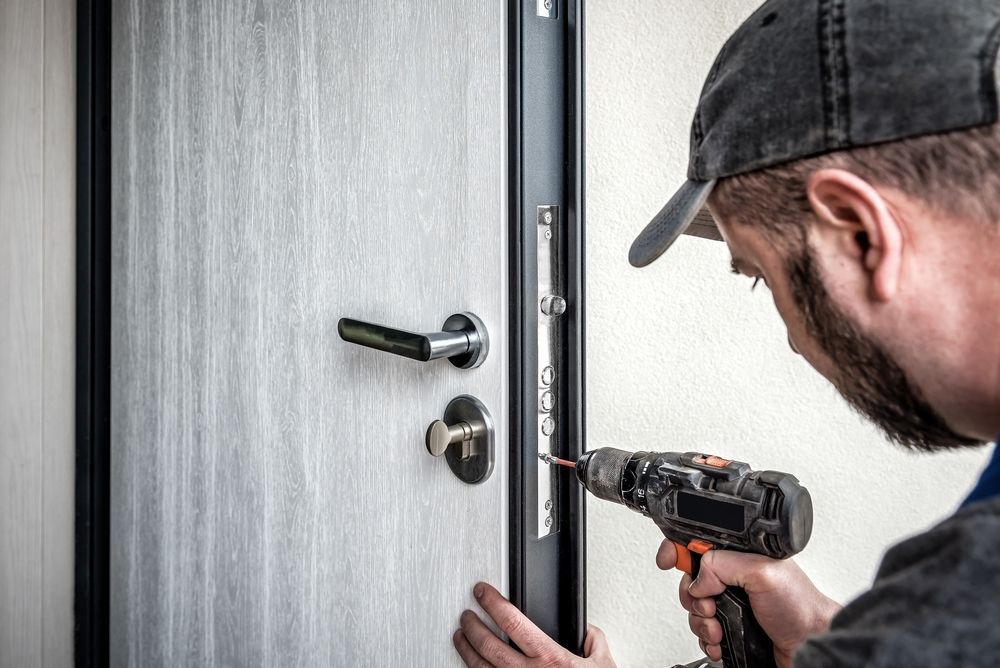 A man is fixing a door with a drill.