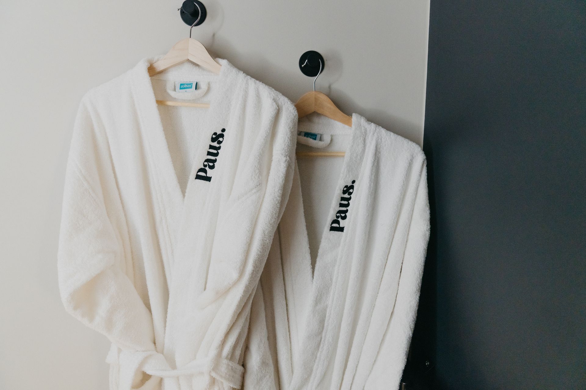 Deux peignoirs blancs sont accrochés au mur.