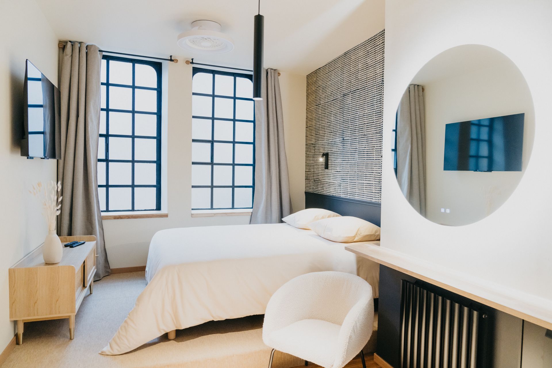 Une chambre avec un lit, une chaise, une télévision et un miroir