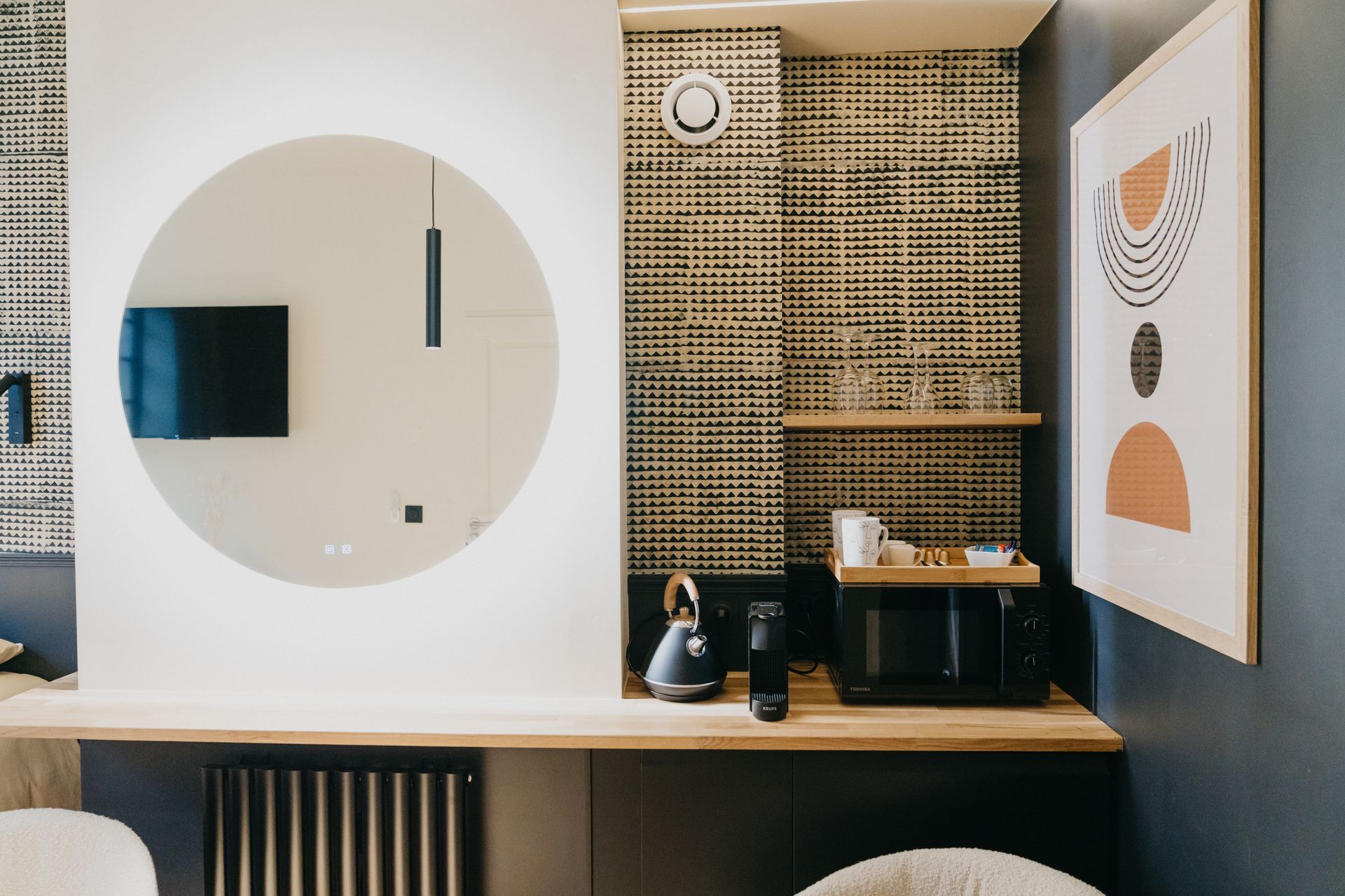 Une chambre d'hôtel avec un bureau, une télévision, un micro-ondes et un miroir.