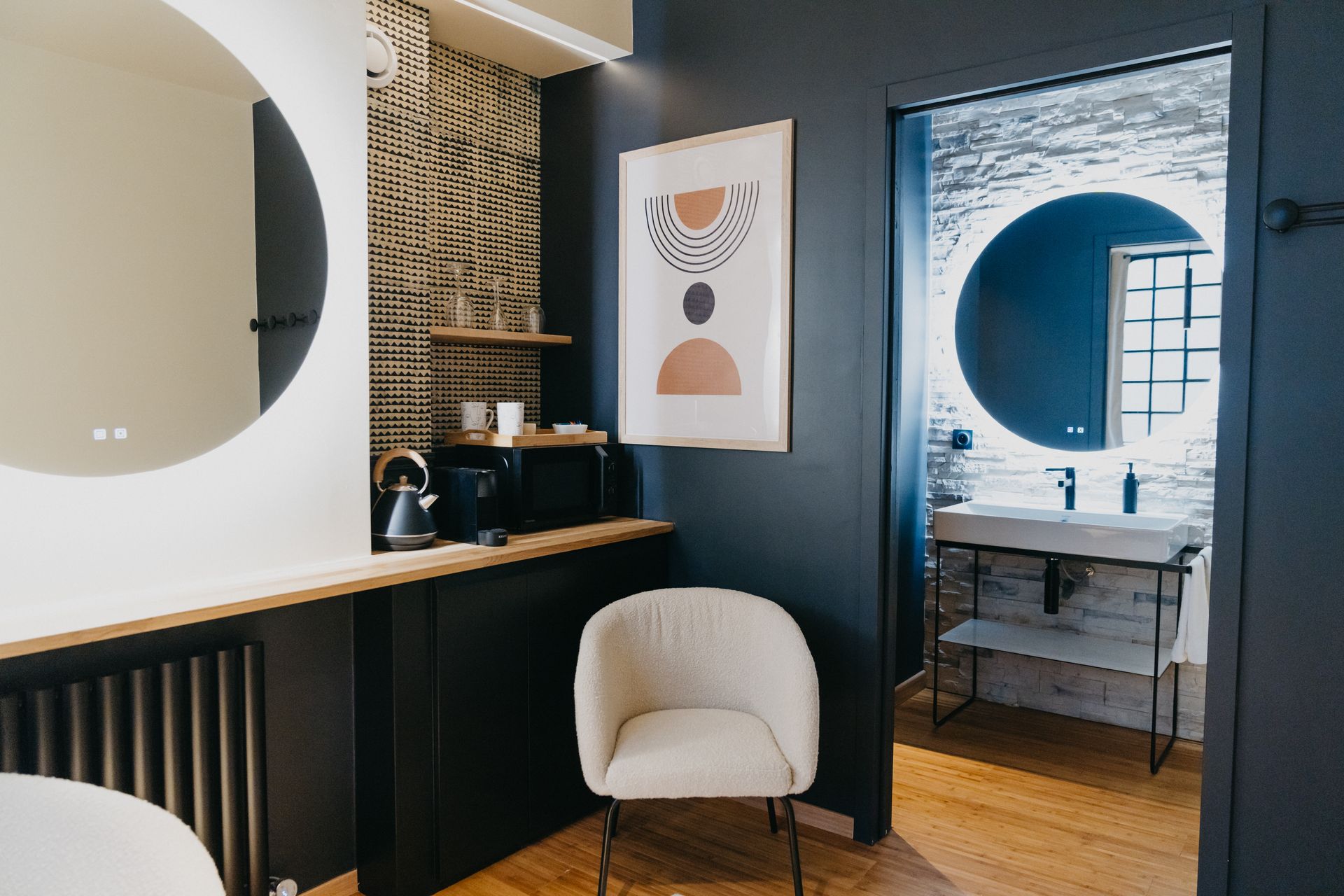 Une salle de bain avec une chaise, un lavabo, des miroirs et un tableau sur le mur.