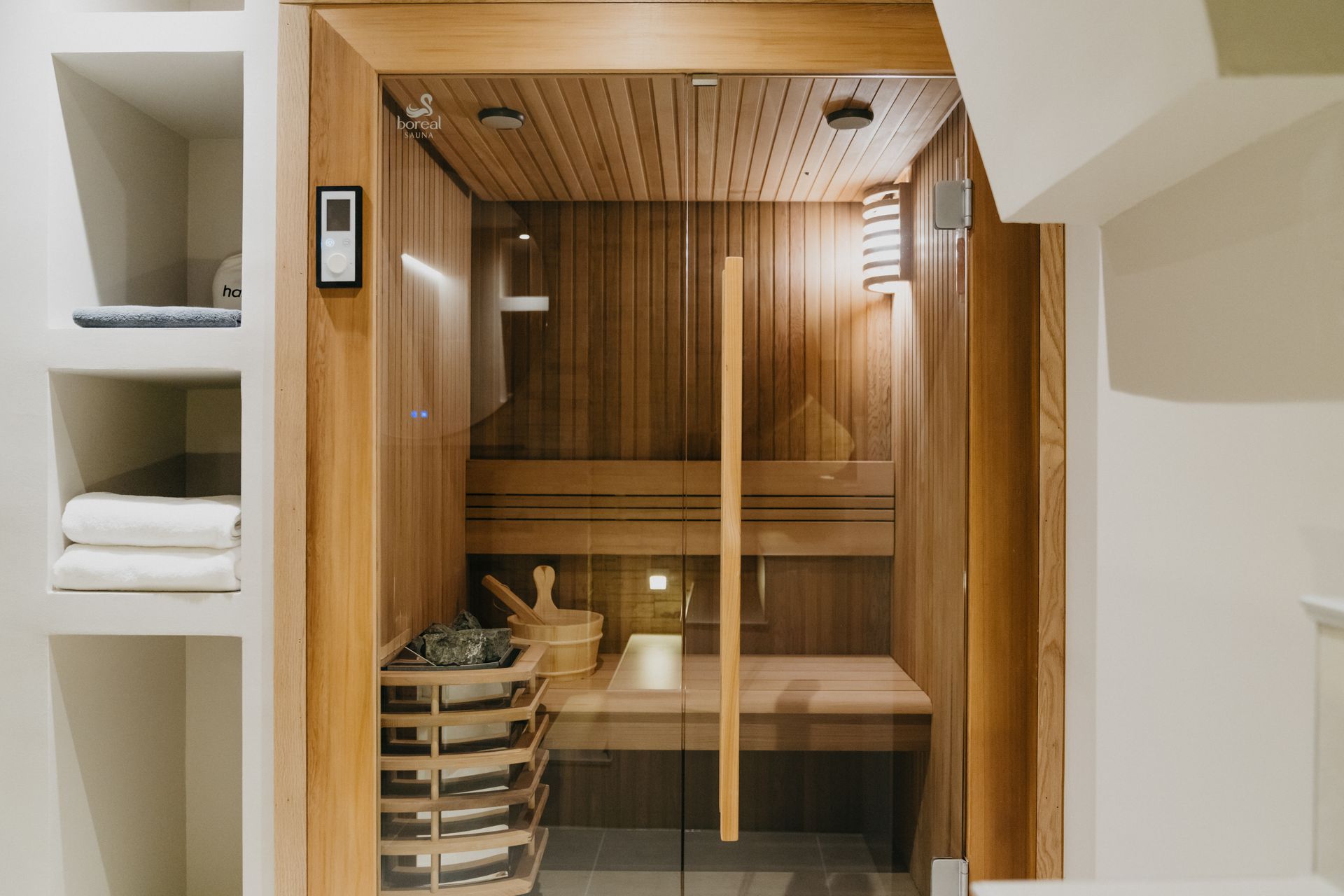 Un sauna en bois avec une porte vitrée dans une salle de bain.