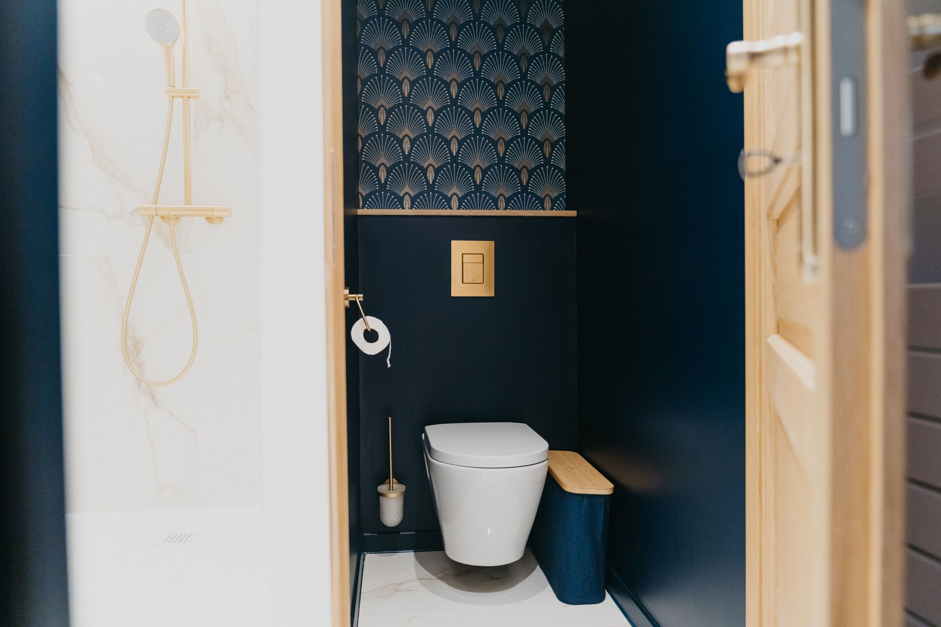 Une salle de bain avec WC, poubelle et douche.