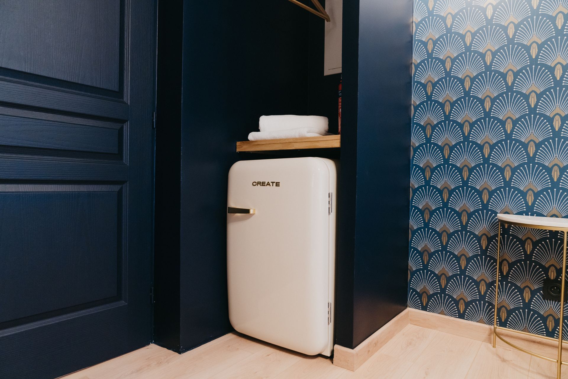 Un petit réfrigérateur blanc se trouve dans le coin d'une salle de bain à côté d'un lavabo.