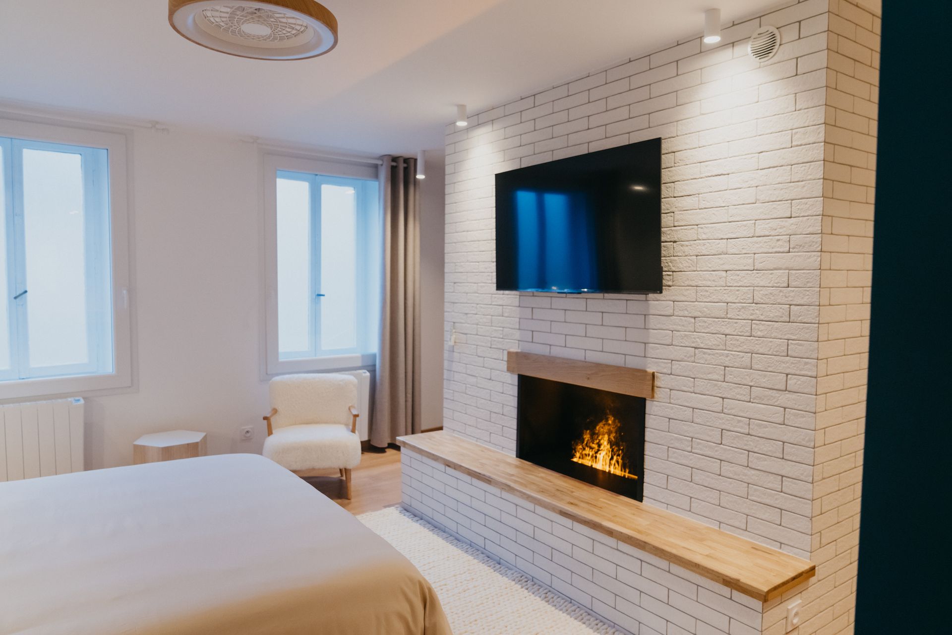 Une chambre avec une cheminée et une télévision à écran plat au mur.