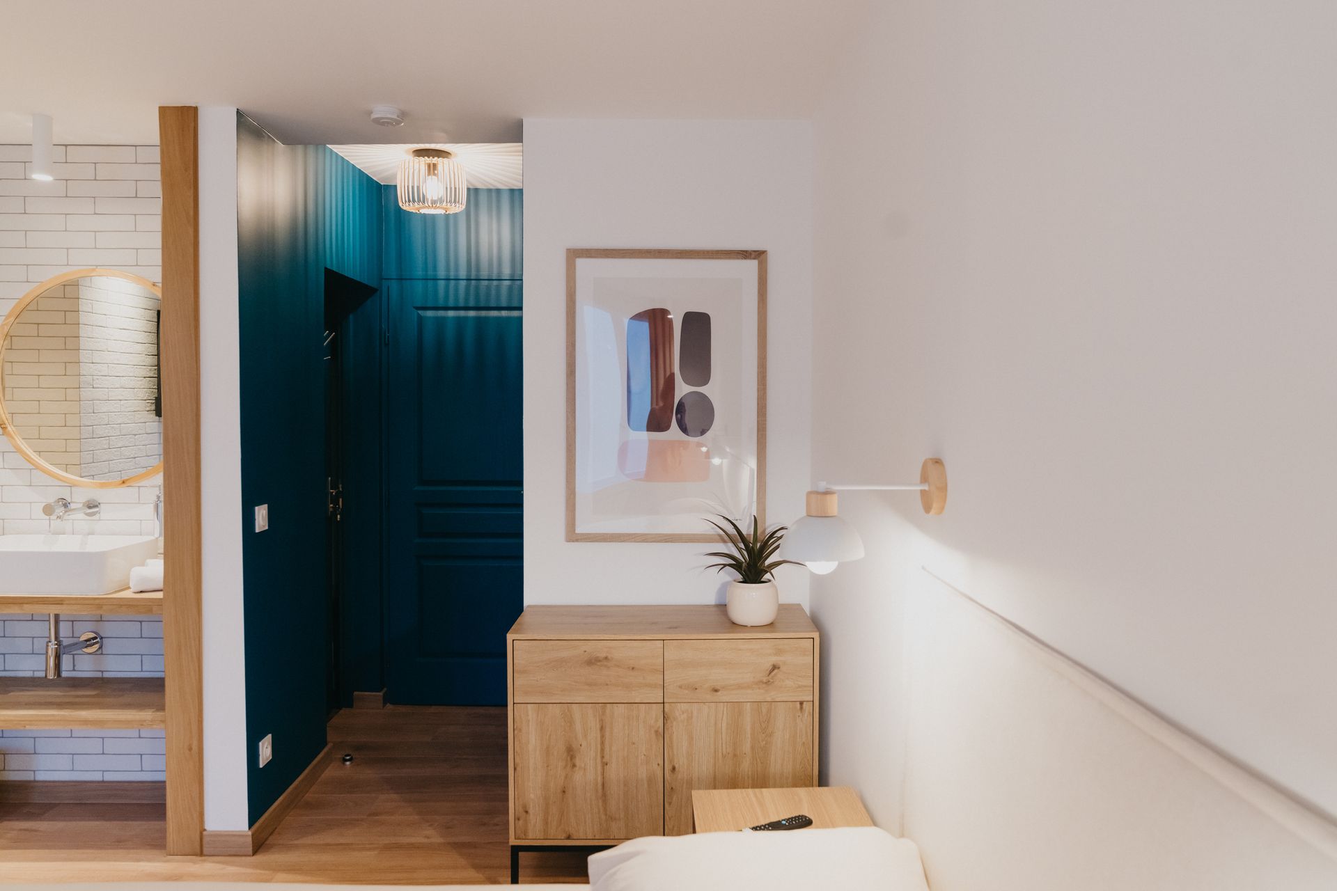 Une chambre avec un lit, une commode, un lavabo et un miroir.