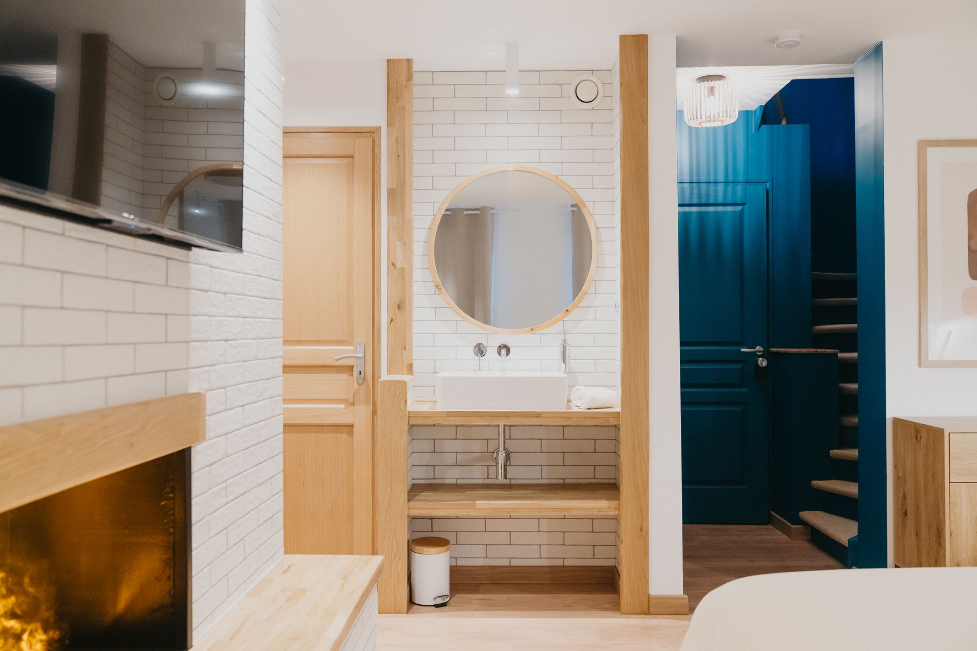 Une salle de bain avec lavabo, miroir et cheminée.