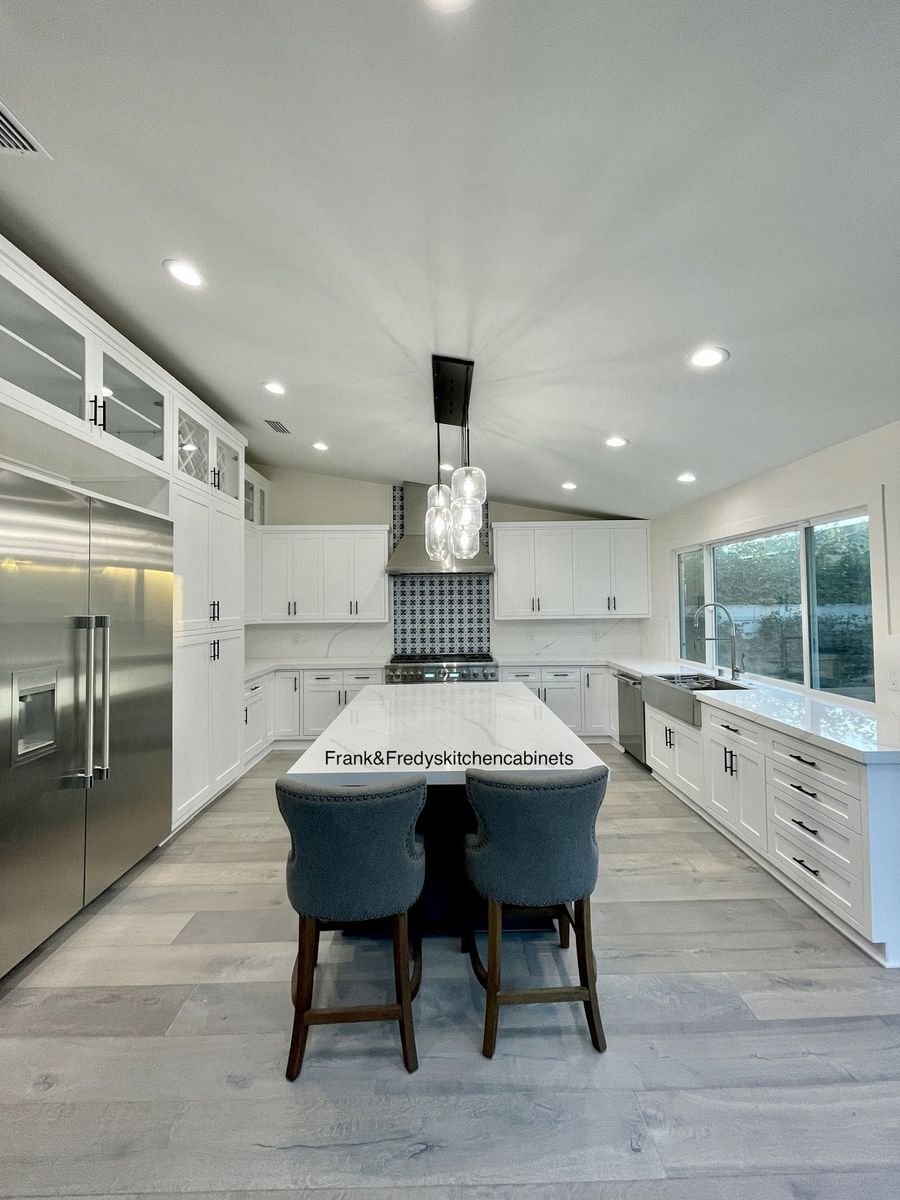 A large kitchen with stainless steel appliances and a large island in the middle.