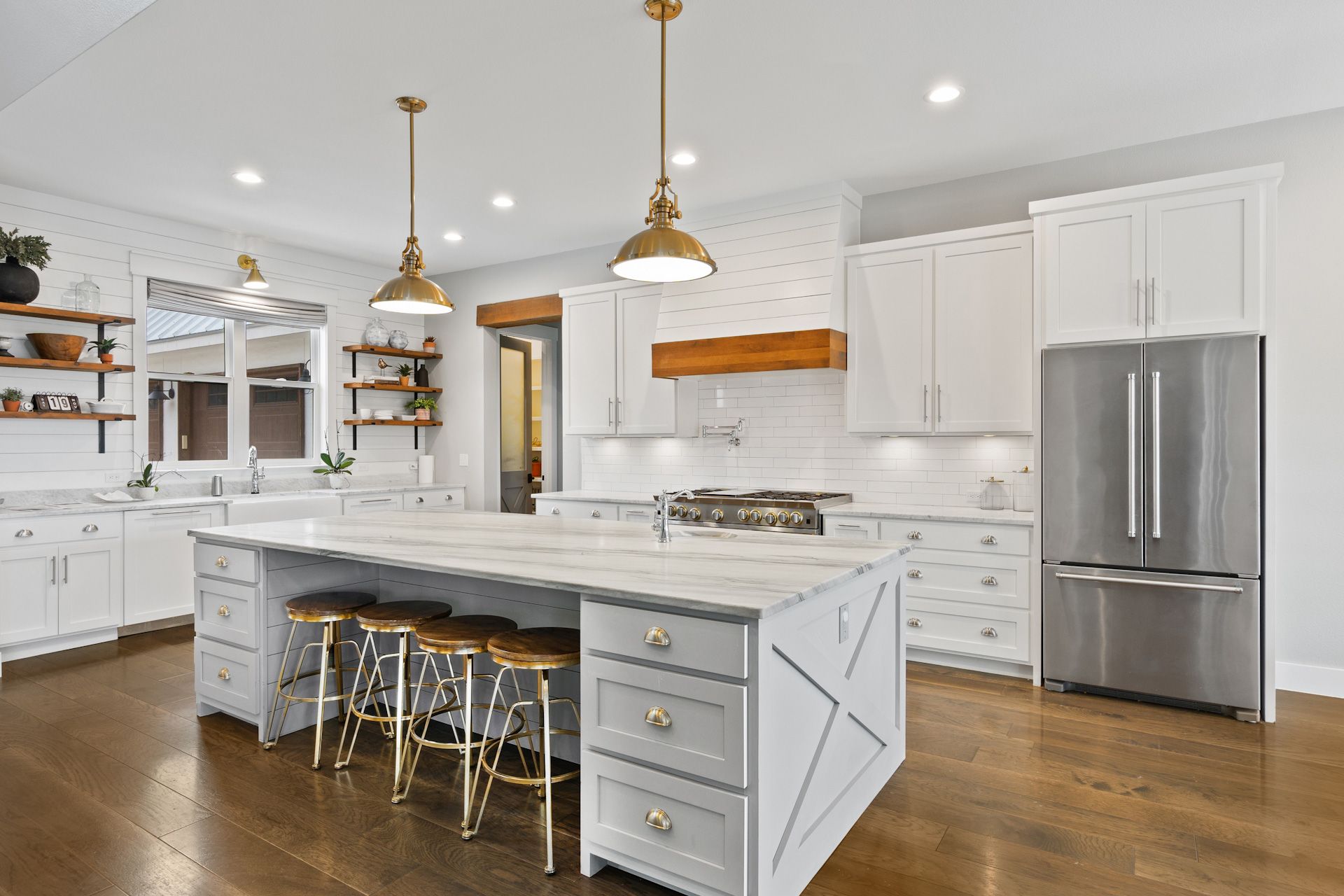 A kitchen with white cabinets, stainless steel appliances, and a large island.