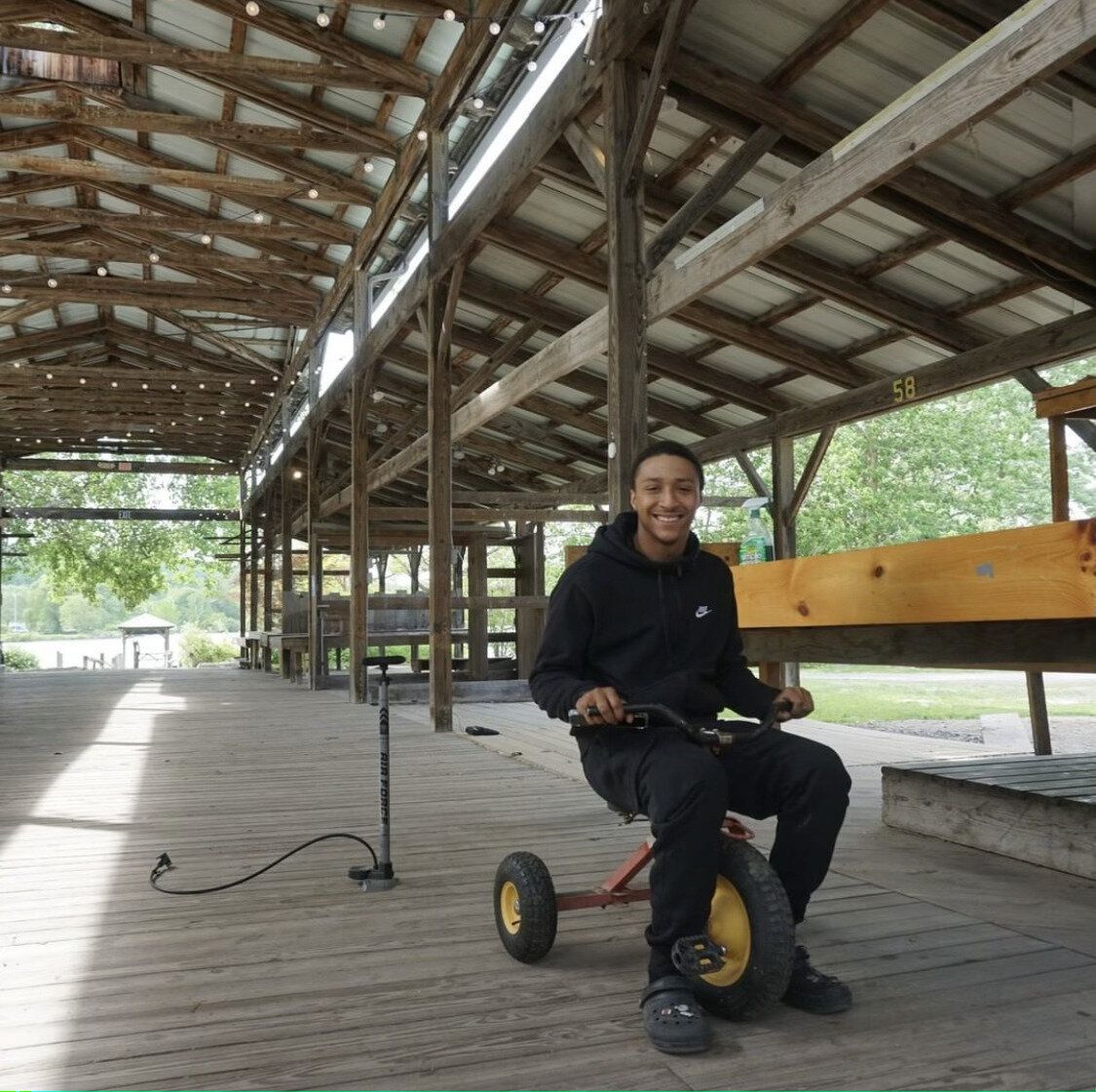 A man is riding a tricycle on a wooden deck