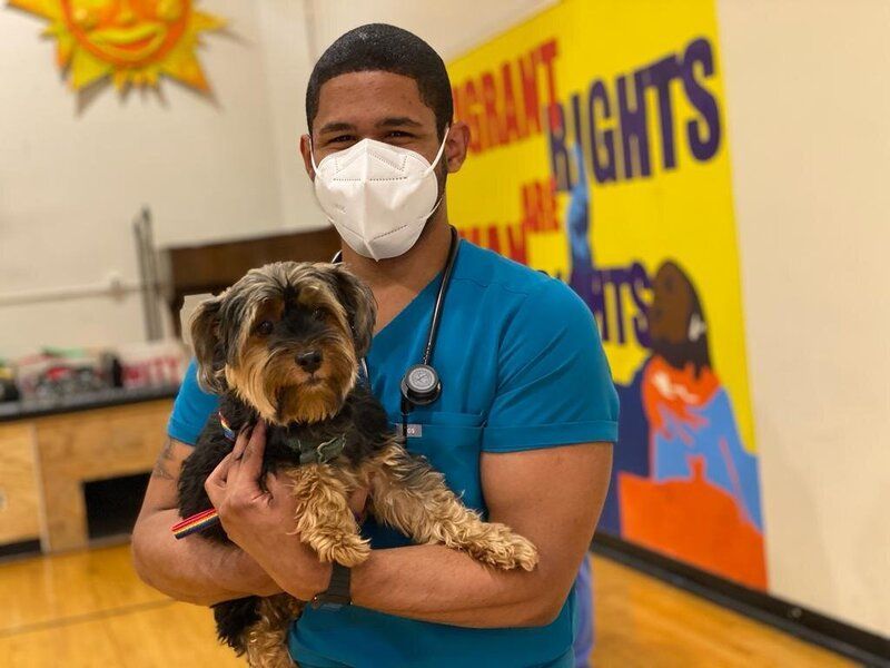 A man wearing a mask is holding a small dog