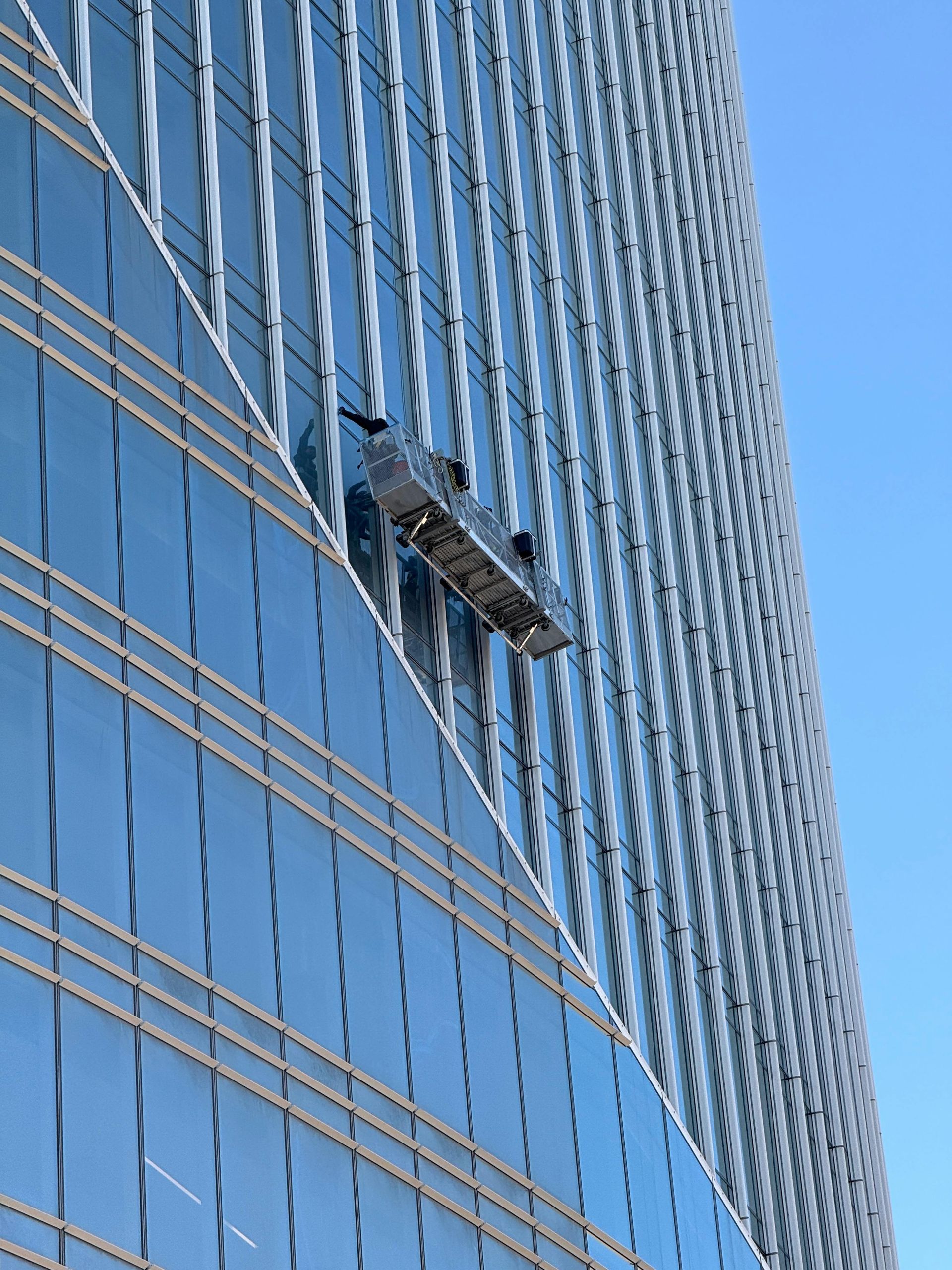 Window washing platform on glass skyscraper facade.