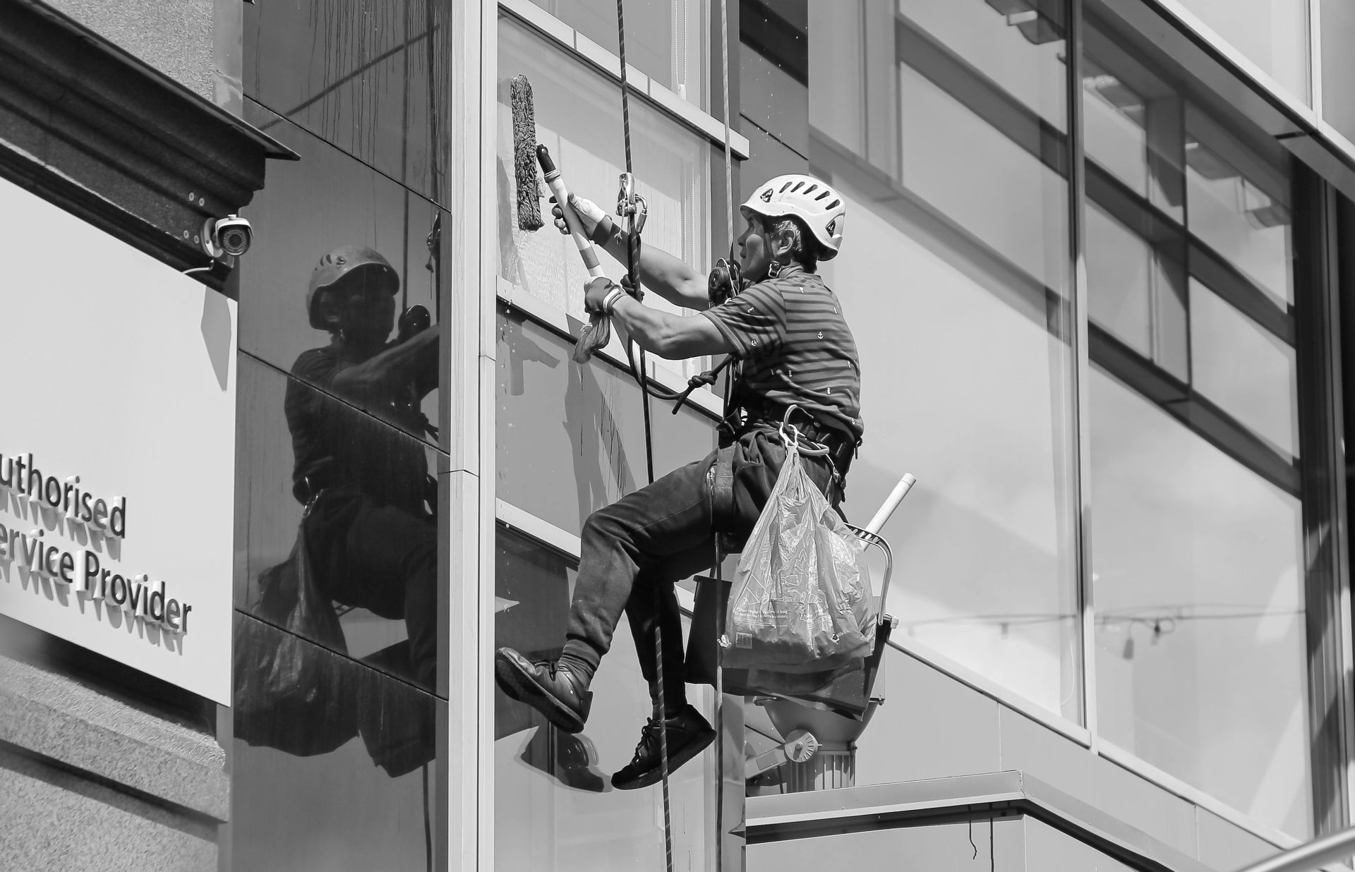 Window washer suspended on ropes cleaning exterior of a building.