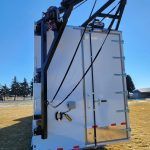 Large white industrial unit lifted by a crane in a grassy field under a blue sky