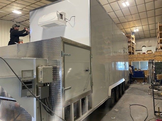Large industrial machine in the Sentinel Trailers warehouse in Idaho Falls, with a person standing on top near the ceiling.
