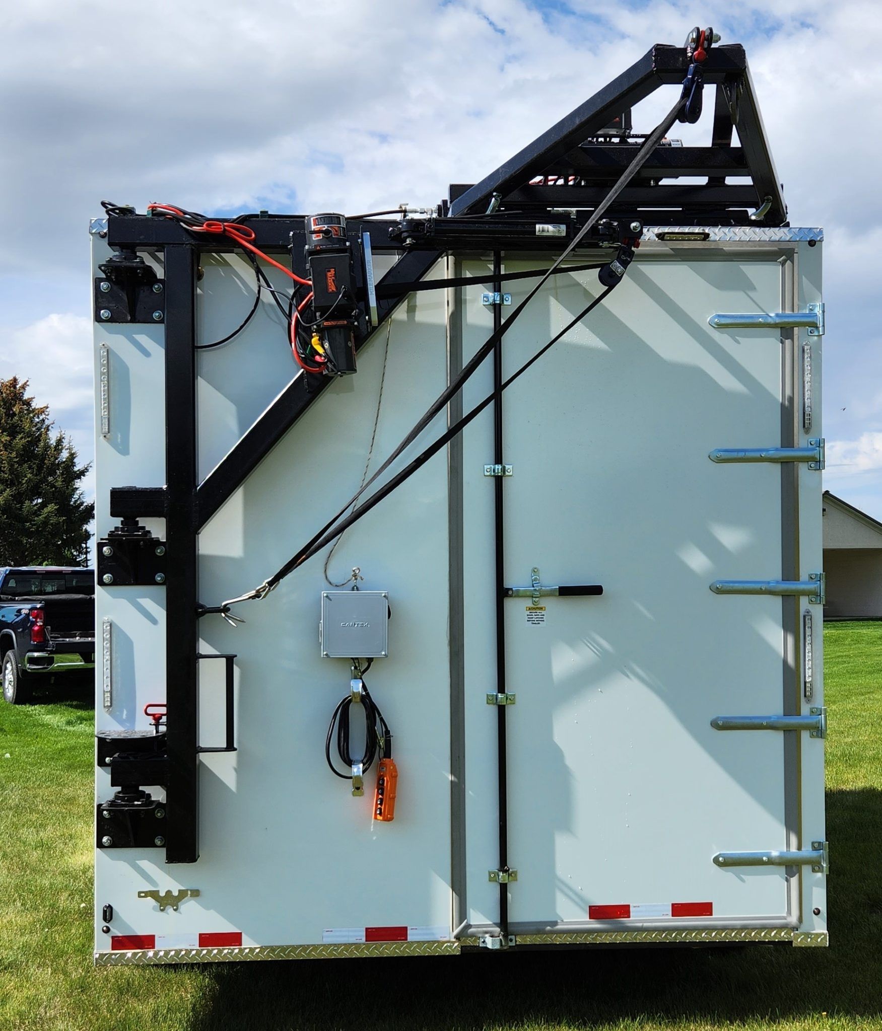 White utility refrigerated trailer with a black roof-mounted boom arm and side-mounted equipment.