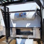 Industrial machine with a white cylindrical tank and black metal frame outdoors