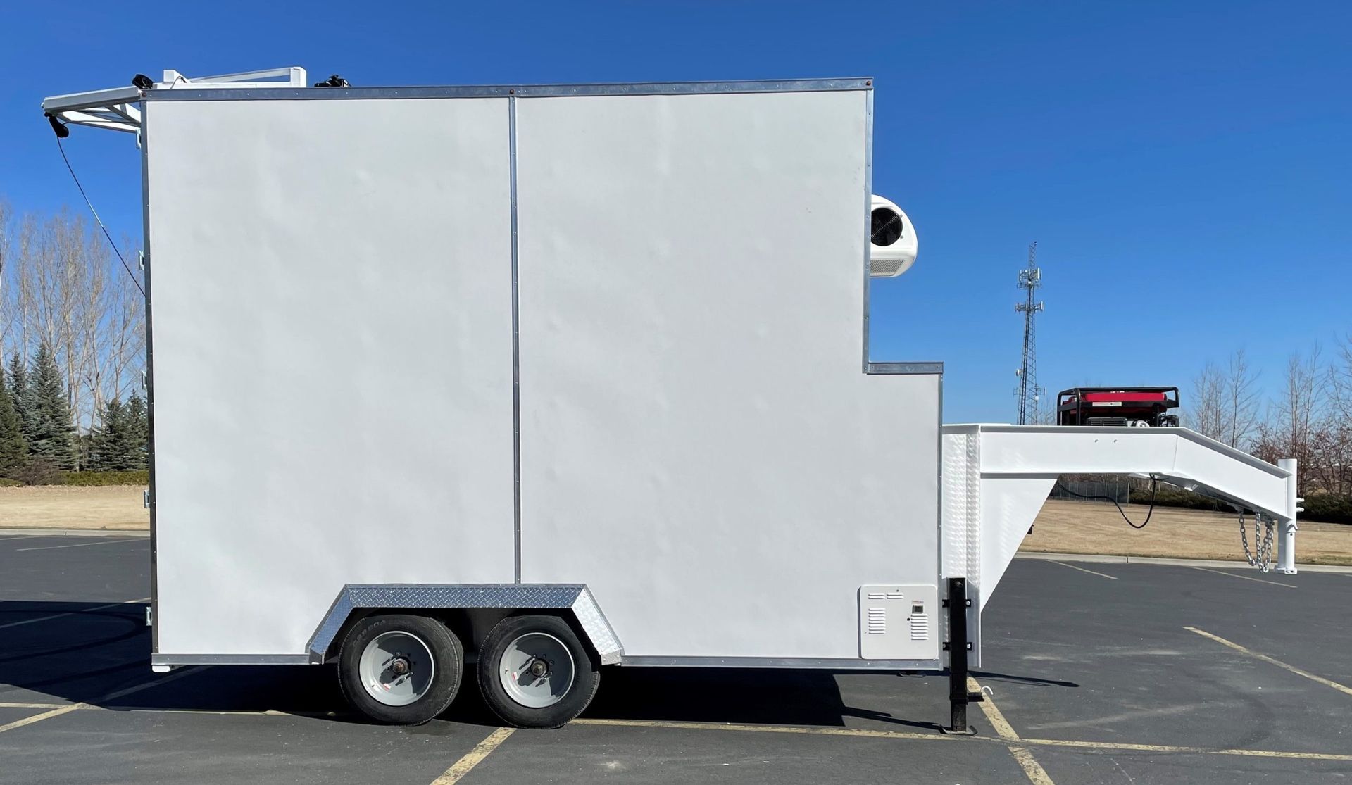White enclosed slaughter trailer parked in a lot, with a side awning and red light on top.