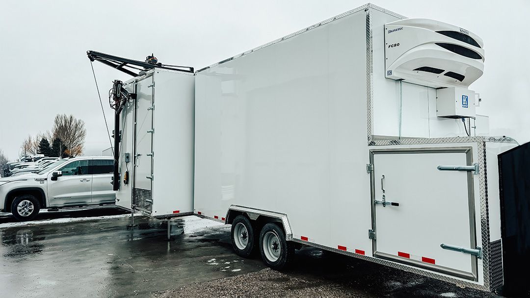 White refrigerated trailer for butcheres truck parked on a wet lot in snowy weather