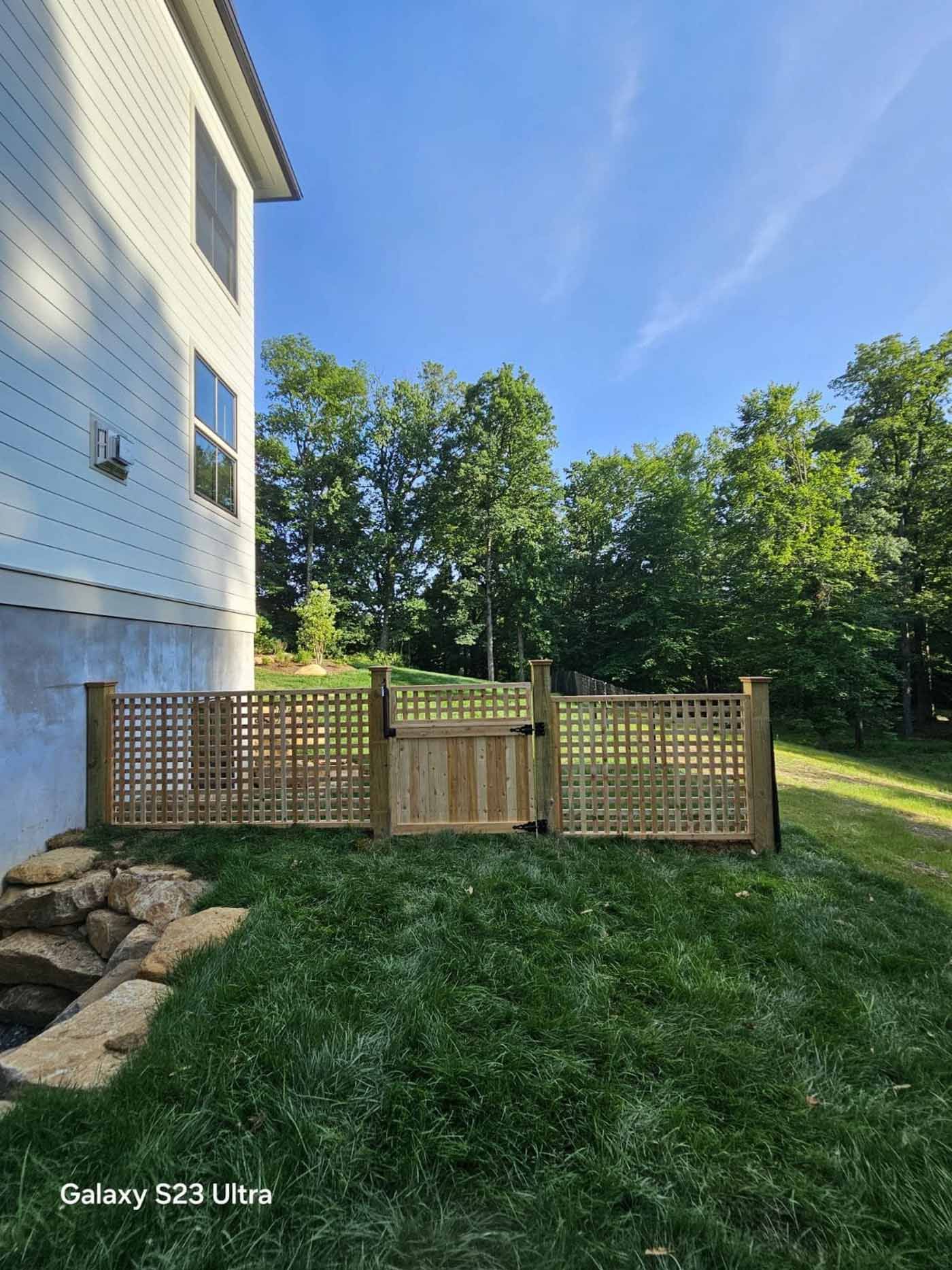 A wooden fence is in the backyard of a house.