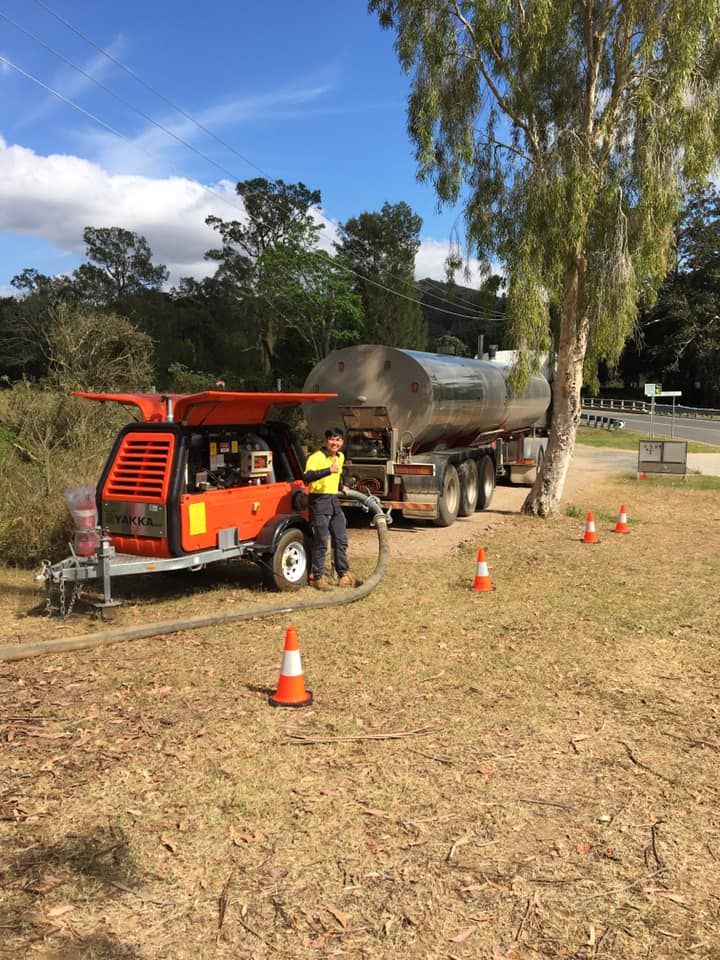 A Man Is Standing Next to A Tanker Truck in A Field — Stolzenberg Water Carriers in Chatsworth, QLD