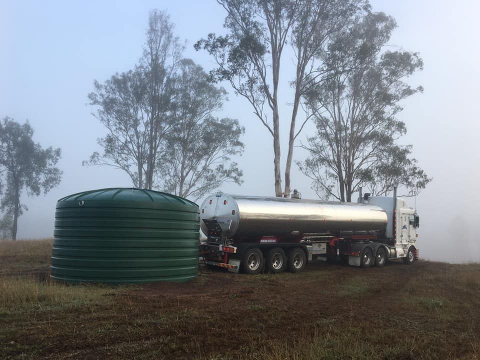 A Tanker Truck Is Parked in A Field Next to A Green Tank — Stolzenberg Water Carriers in Curra, QLD