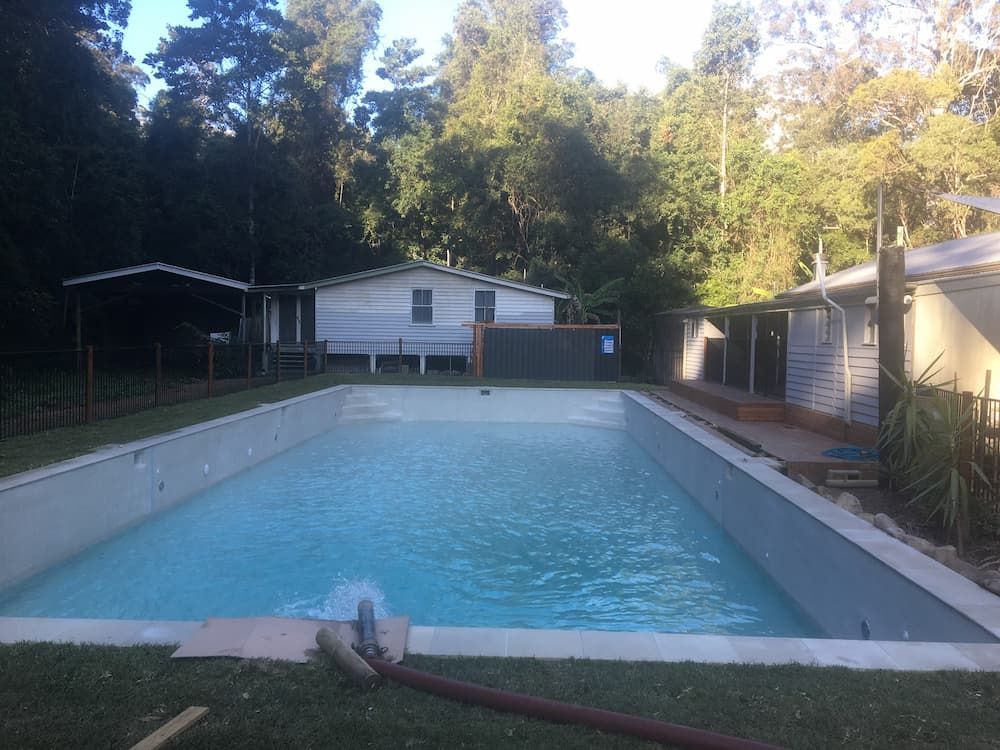A Large Swimming Pool with A House in The Background — Stolzenberg Water Carriers in Chatsworth, QLD