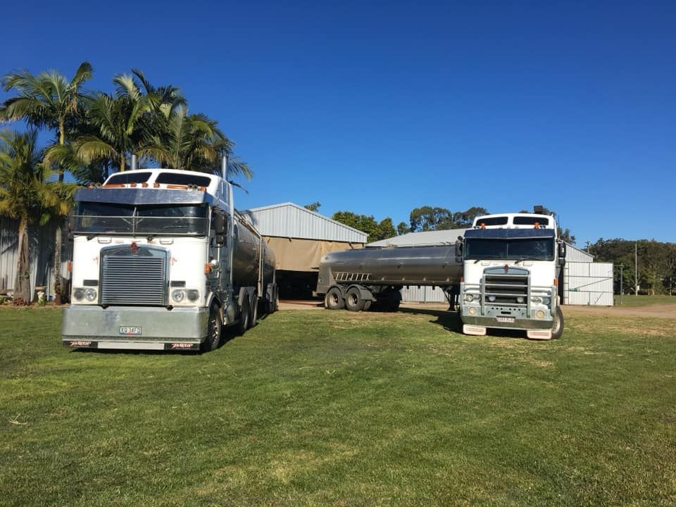 Two Semi Trucks Are Parked Next to Each Other in A Grassy Field — Stolzenberg Water Carriers in Chatsworth, QLD