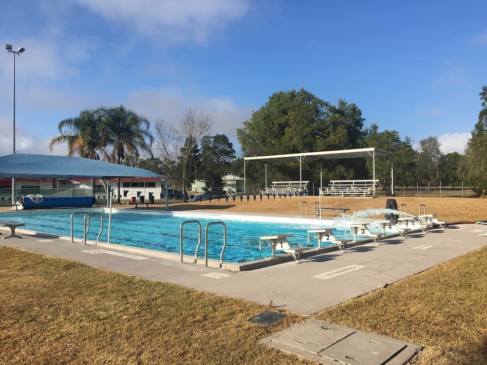 A Large Swimming Pool with A Volleyball Net in The Background — Stolzenberg Water Carriers in Chatsworth, QLD
