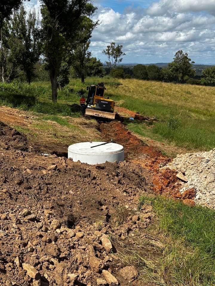 A Bulldozer Is Digging a Hole And A White Septic Tank — Stolzenberg Water Carriers in Gympie, QLD