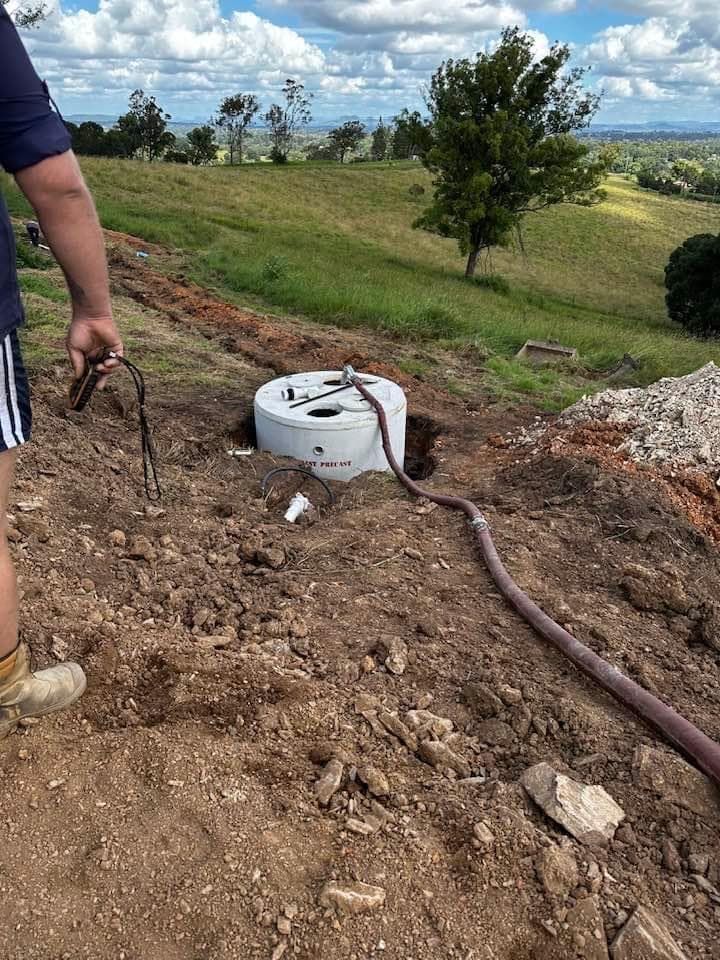 A Man Is Standing Next to A Manhole Cover in The Dirt — Stolzenberg Water Carriers in Chatsworth, QLD