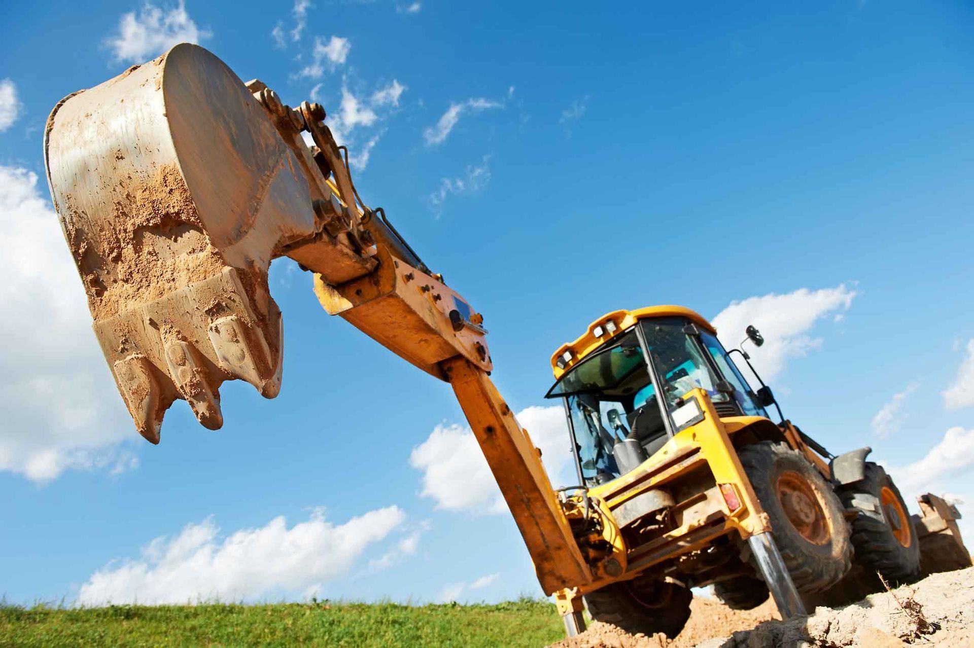 A Yellow Excavator Is Digging A Hole In A Field – Port Pirie, SA - Flinders Earthmoving & Blue Metal Supplies