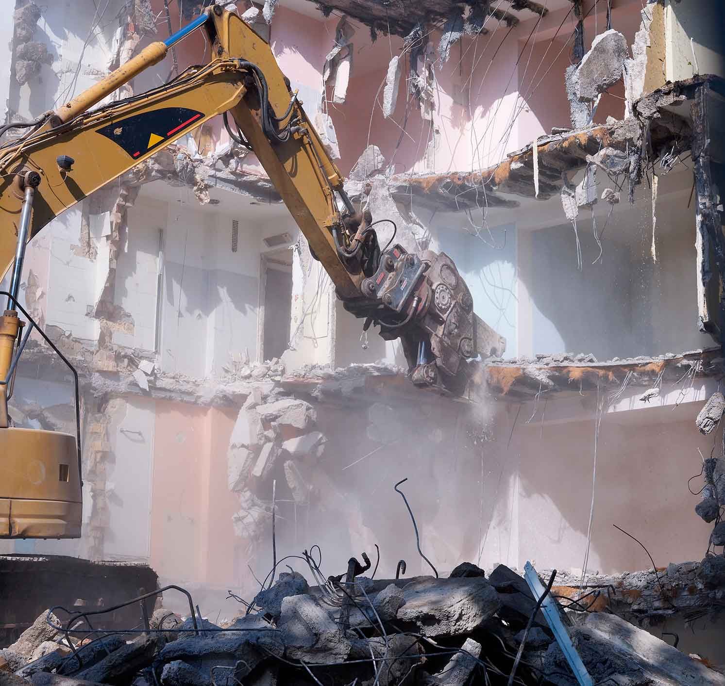 A Sizable Yellow Excavator Is In The Process Of Demolishing A Building – Port Pirie, SA - Flinders Earthmoving & Blue Metal Supplies