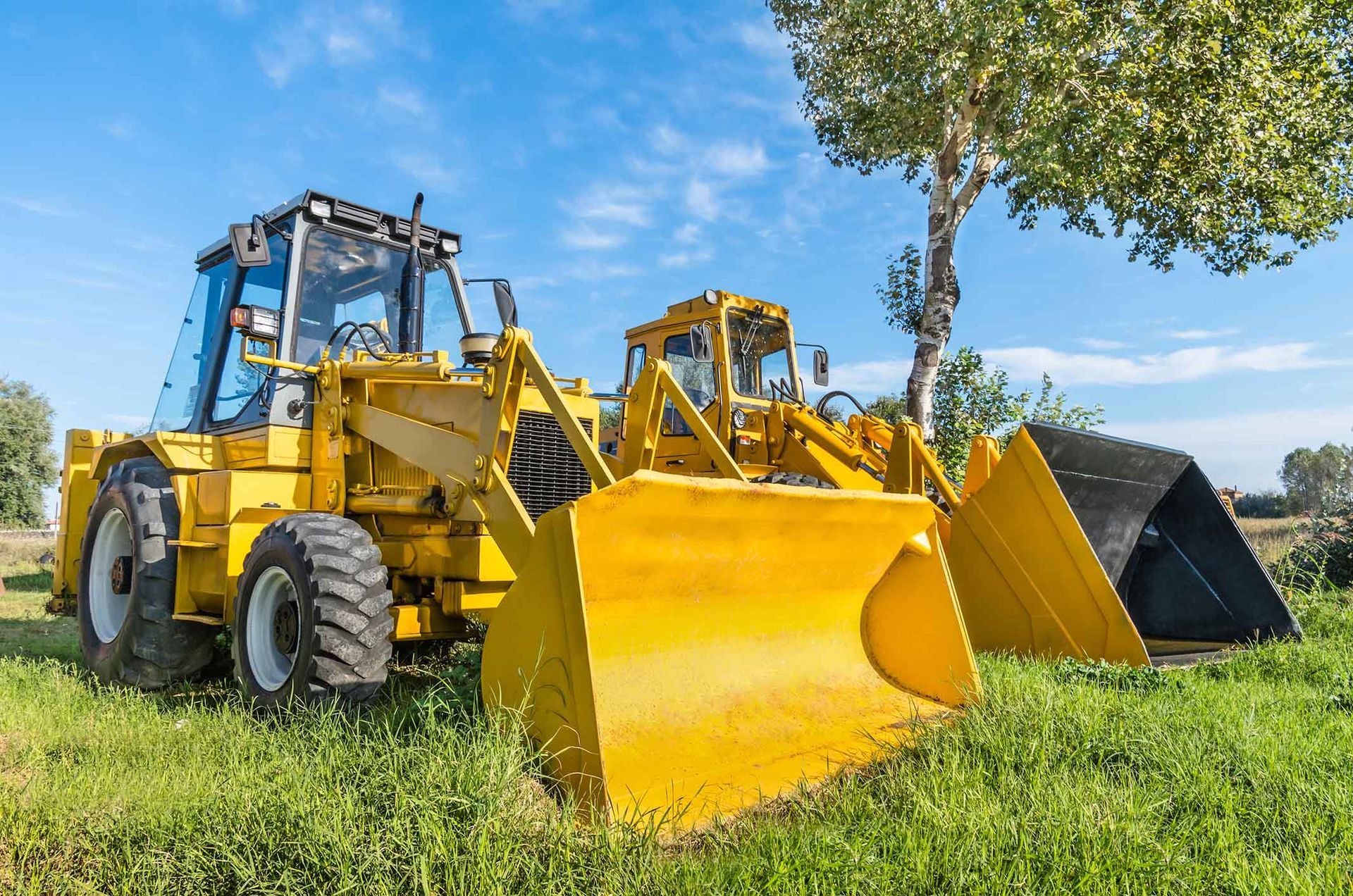 Two Yellow Bulldozers Are Parked In A Grassy Field – Port Pirie, SA - Flinders Earthmoving & Blue Metal Supplies