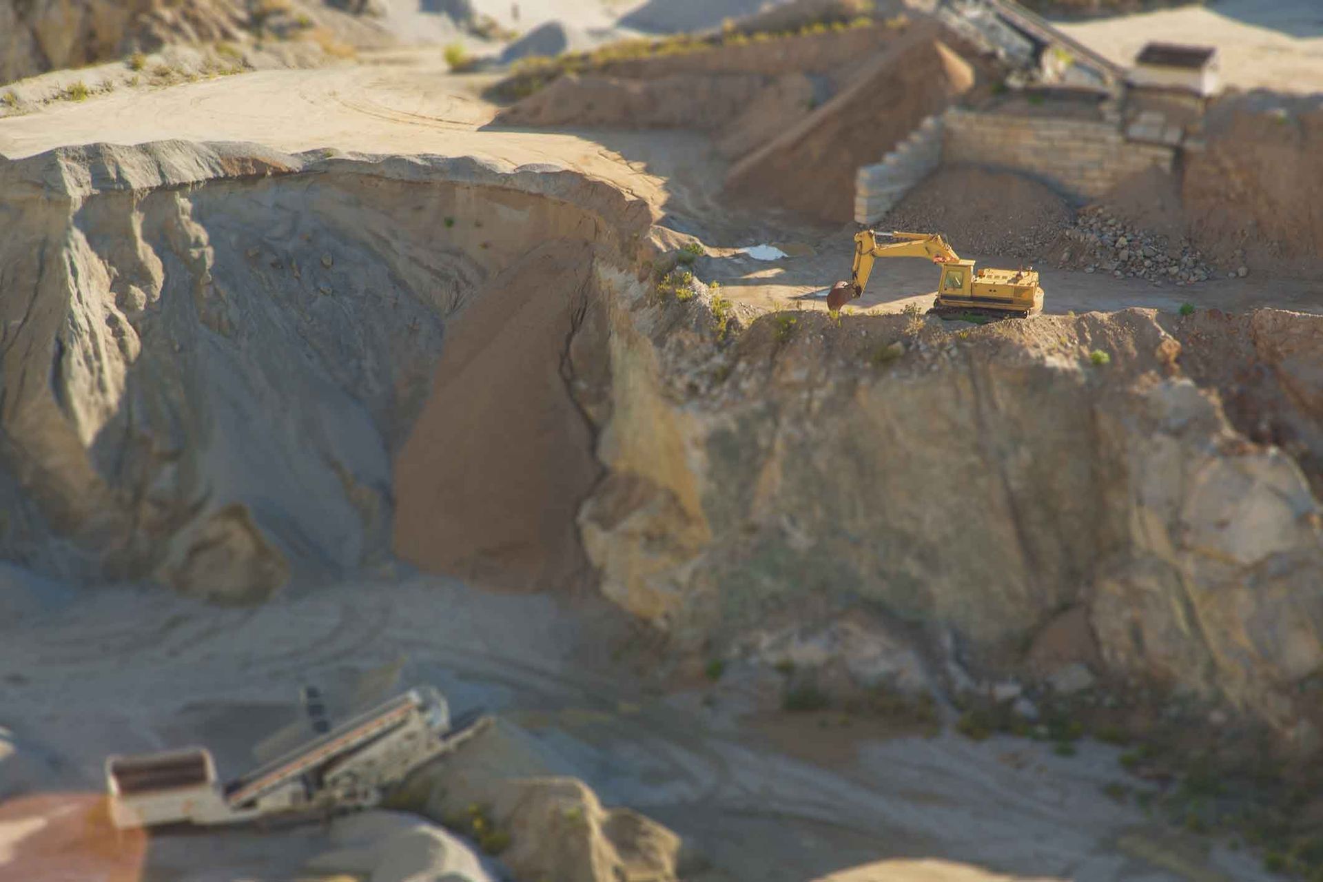 A Yellow Excavator Is Sitting On Top Of A Rocky Hill In A Quarry – Port Pirie, SA - Flinders Earthmoving & Blue Metal Supplies