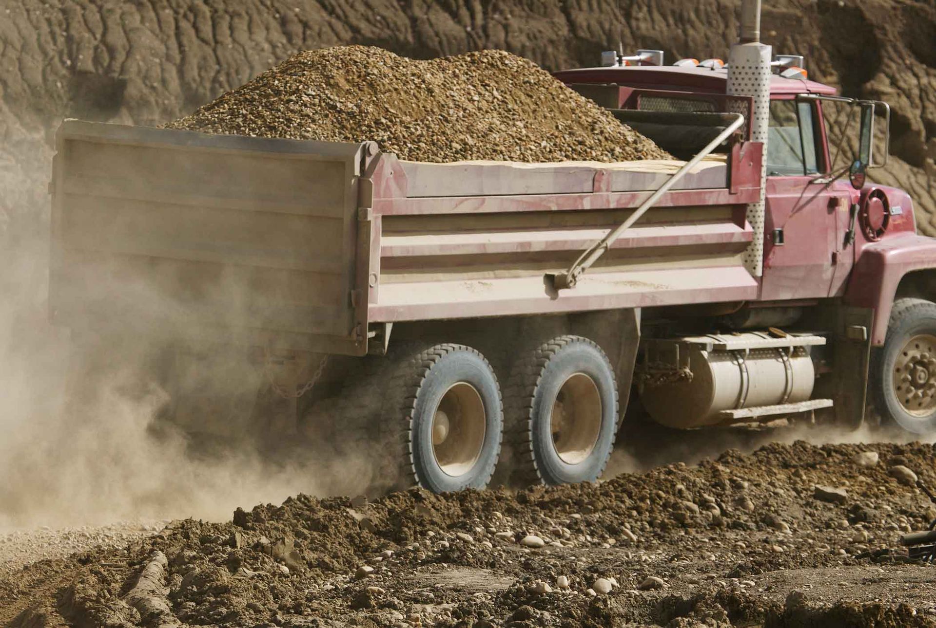 A Red Dump Truck Is Driving Down A Dirt Road – Port Pirie, SA - Flinders Earthmoving & Blue Metal Supplies